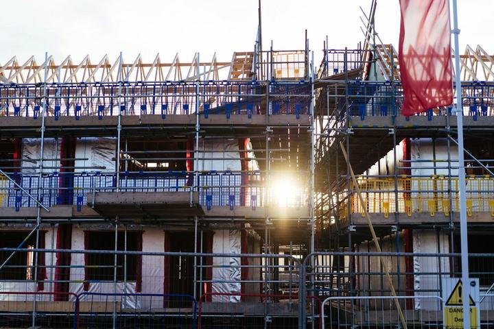 Multi-story building under construction, wrapped in scaffolding