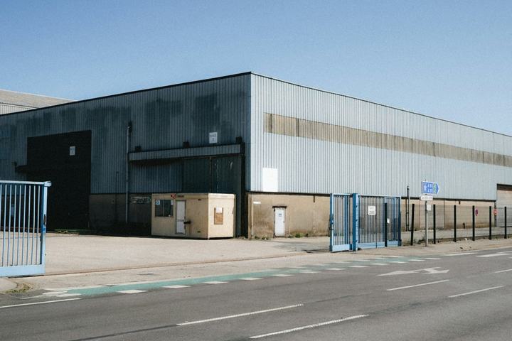 Large industrial warehouse building with loading gates beside a road