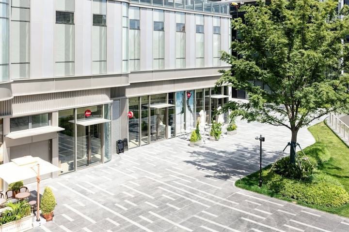 Ground-floor retail storefronts facing a landscaped plaza